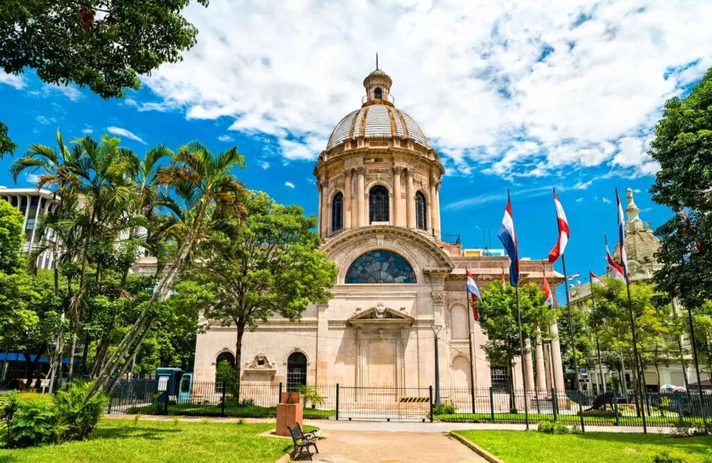 El Panteón Nacional de los Héroes, con su cúpula y banderas de Paraguay en la vereda, rodeado de palmeras