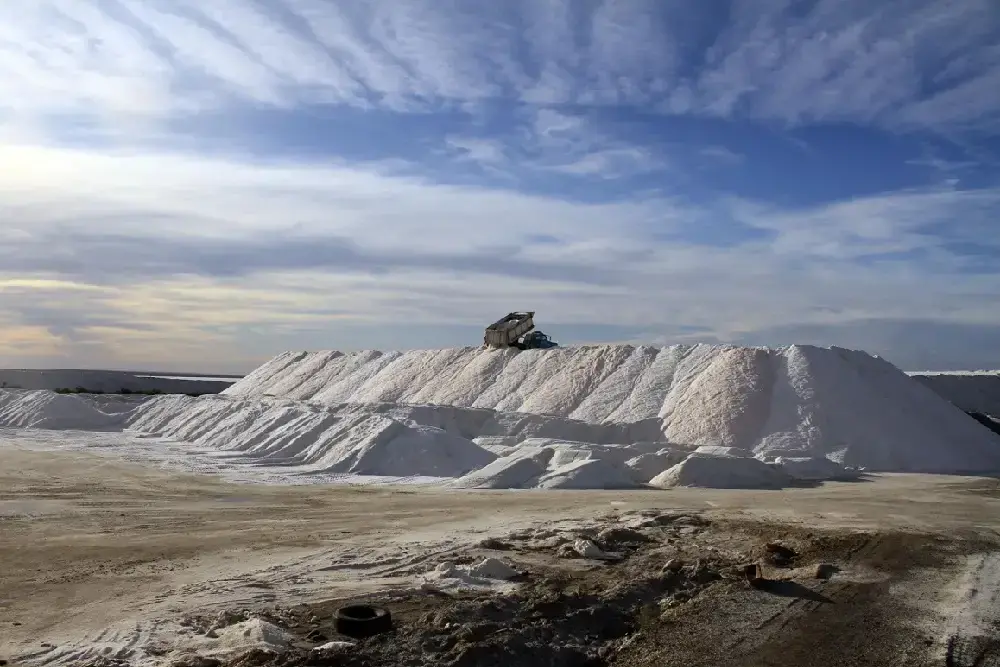 Montañas de sal blanca con un camión en la cima, bajo un cielo con nubes largas