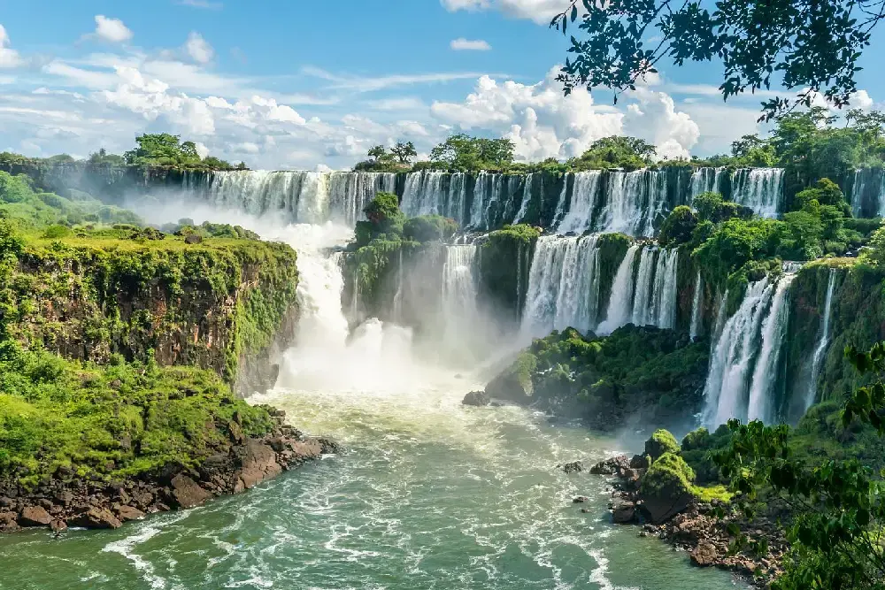 Panorámica de las Cataratas del Iguazú: decenas de saltos cayendo sobre paredes cubiertas de vegetación, con el río abajo