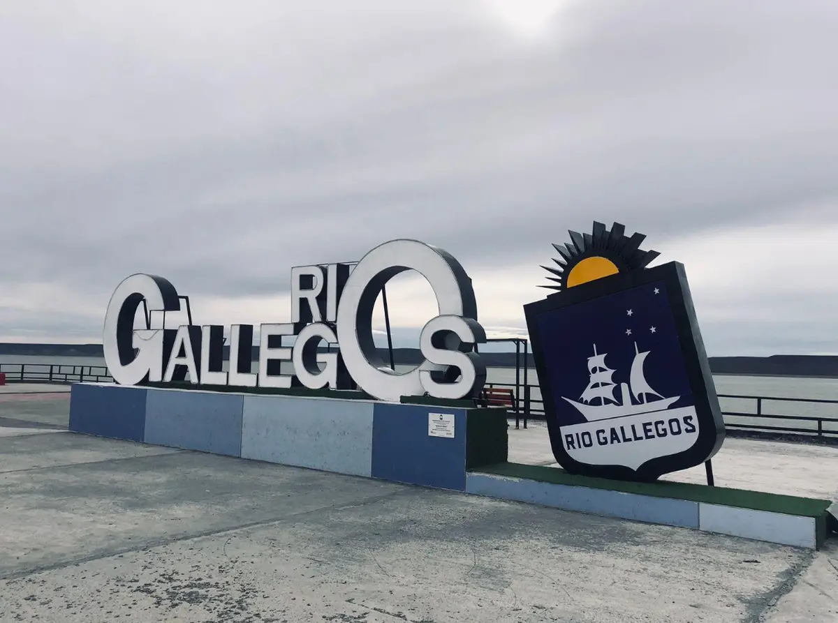Las letras corpóreas de Río Gallegos y el escudo de la ciudad, con un velero y un sol, sobre la costanera frente a la ría en un día nublado