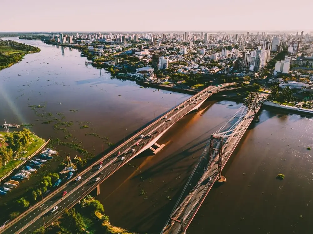 Vista aérea de Santa Fe con dos puentes sobre la laguna, uno de ellos el Colgante, y la ciudad con sus edificios detrás