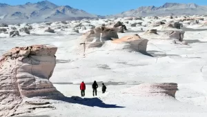 Tres personas observando un paisaje de piedras gigantes y arena