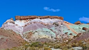 Cerros de distintos colores y tamaños con el cielo de fondo y rodeado de verde