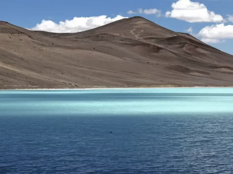Laguna azul de agua cristalina con montañas de fondo