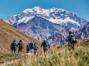 Turistas recorriendo el Parque Provincial Aconcagua rodeado de montañas y pasto